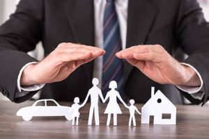 Concept of insurance with hands over a house, a car and a family