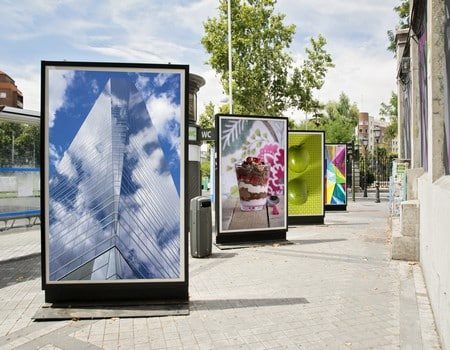 4 vallas publicitarias con fotografías mostradas en una calle de la ciudad